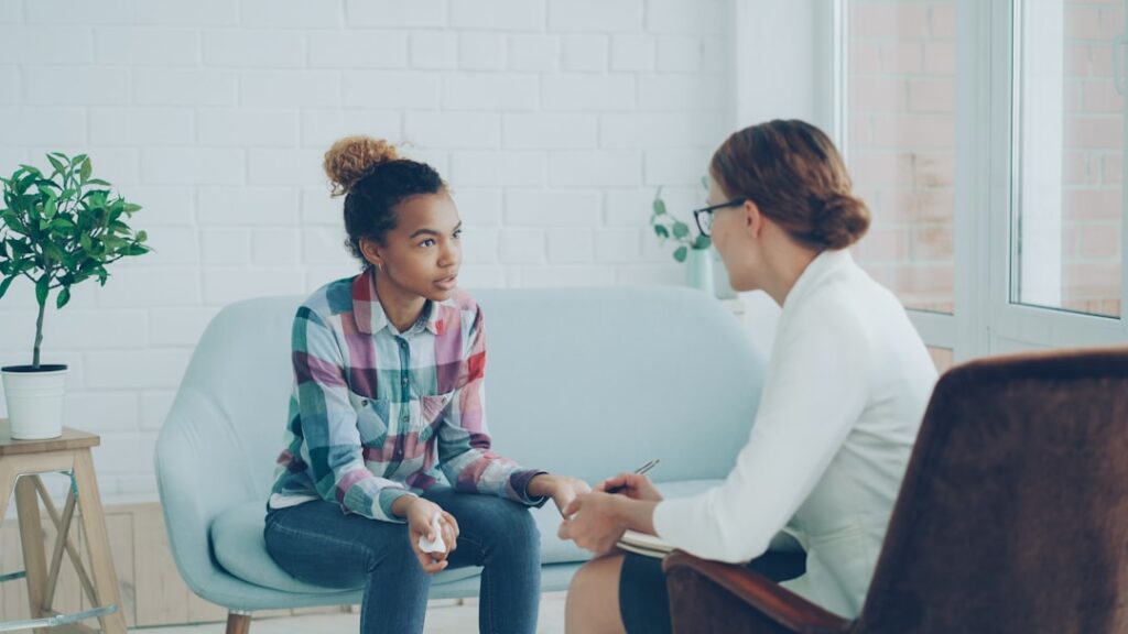 Therapist talking to a young woman on couch.